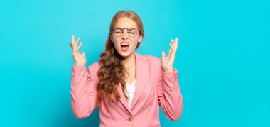 Sarışın, güzel bir kadın öfkeyle bağırıyor, stresli ve elleri havada neden ben diye bağırıyor.