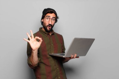 Laptoplu genç sakallı adam.