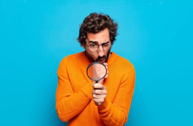 Büyüteçle genç sakallı adam.