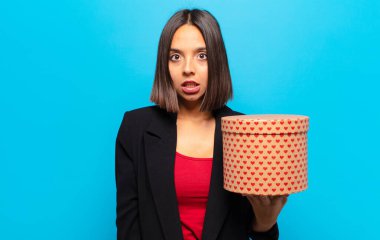 Genç ve güzel bir kadın elinde bir hediye kutusu tutuyor.