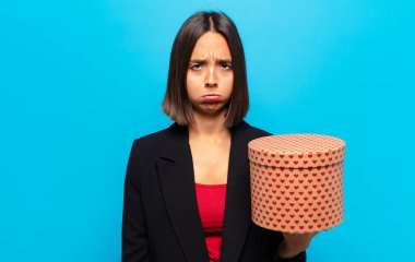 Genç ve güzel bir kadın elinde bir hediye kutusu tutuyor.