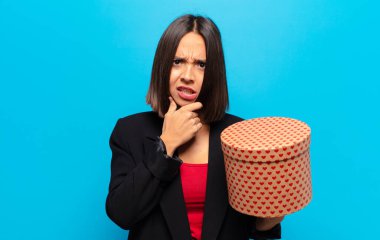 Genç ve güzel bir kadın elinde bir hediye kutusu tutuyor.