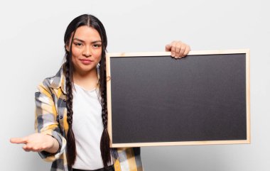 İspanyol kadın mutlu bir şekilde gülümsüyor arkadaş canlısı, kendinden emin, olumlu bakışlı, bir nesne ya da konsept sunuyor ve gösteriyor.