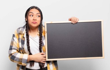 İspanyol kadın omuz silkiyor, kafası karışık ve emin değil, kolları bağlı ve şaşkın bir şekilde şüpheli bakıyor.