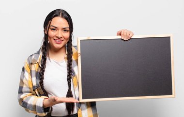 İspanyol kadın mutlu bir şekilde gülümsüyor, mutlu hissediyor ve fotokopi uzayında bir konsept gösteriyor.