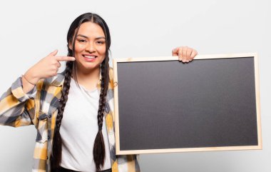 İspanyol kadın kendine güvenerek gülümsüyor. Kendi gülüşünü gösteriyor. Olumlu, rahat, tatmin olmuş tavır.