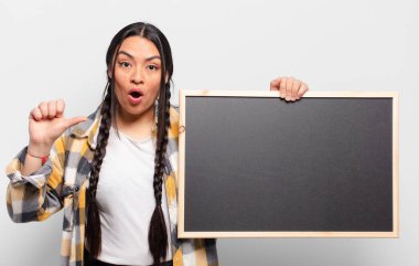 İspanyol kadın inançsızlıktan şaşkın şaşkın bakıyor, yan taraftaki objeyi işaret ediyor ve diyor ki: