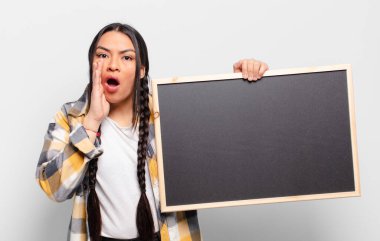 İspanyol kadın şok olmuş ve korkmuş hissediyor, ağzı açık ve elleri yanaklarında korkmuş görünüyor.