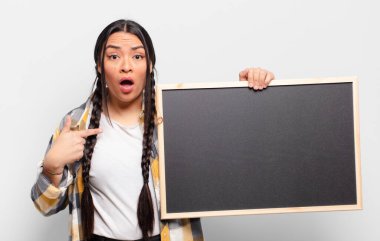 İspanyol kadın şok olmuş ve şaşırmış görünüyor, ağzı açık, kendini işaret ediyor.