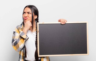 Hispanik kadın düşünüyor, şüpheci ve şaşkın hissediyor, farklı seçeneklerle, hangi kararı vereceğini merak ediyor.