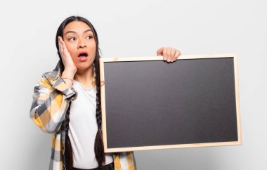 Hispanik kadın mutlu, heyecanlı ve şaşırmış hissediyor, iki eli yüzü yana bakıyor