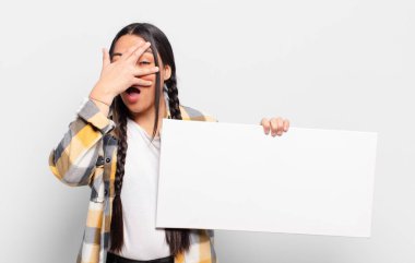 İspanyol kadın şok olmuş, korkmuş ya da korkmuş görünüyor. Yüzü elle kaplanmış ve parmaklarının arasından gizlice bakıyor.