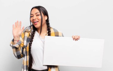 İspanyol kadın mutlu ve neşeli bir şekilde gülümsüyor, el sallıyor, seni selamlıyor ve selamlıyor, ya da hoşça kal diyor.