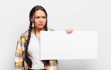 Hispanik kadın üzgün, üzgün ya da kızgın ve olumsuz bir tavır takınıyor, anlaşmazlık içinde kaşlarını çatıyor.