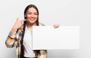 İspanyol kadın kendine güvenerek gülümsüyor. Kendi gülüşünü gösteriyor. Olumlu, rahat, tatmin olmuş tavır.