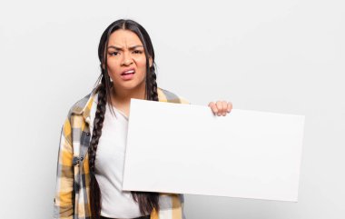 hispanic woman feeling puzzled and confused, with a dumb, stunned expression looking at something unexpected