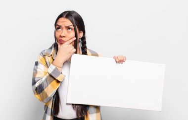 Hispanik kadın düşünüyor, şüpheci ve şaşkın hissediyor, farklı seçeneklerle, hangi kararı vereceğini merak ediyor.