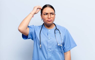 İspanyol kadın şaşkın ve şaşkın hissediyor, kafasını kaşıyor ve yan tarafa bakıyor.