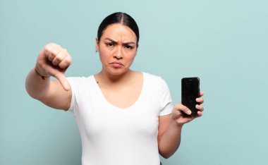 Hispanik kadın kızgın, sinirli, hayal kırıklığına uğramış ya da hoşnutsuz, ciddi bir bakışla başparmaklarını göstermiyor.