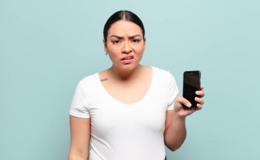 hispanic woman feeling puzzled and confused, with a dumb, stunned expression looking at something unexpected