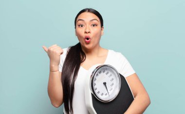 İspanyol kadın inançsızlıktan şaşkın şaşkın bakıyor, yan taraftaki objeyi işaret ediyor ve diyor ki: