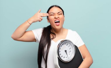 İspanyol kadın mutsuz ve stresli görünüyor, intihar jesti elle silah işareti yapıyor, kafasını işaret ediyor.