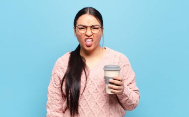 İspanyol kadın tiksinmiş ve rahatsız olmuş hissediyor, dilini dışarı çıkarıyor, iğrenç ve iğrenç bir şeyden hoşlanmıyor.