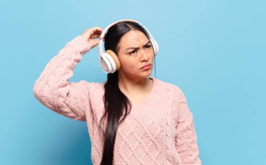 İspanyol kadın şaşkın ve şaşkın hissediyor, kafasını kaşıyor ve yan tarafa bakıyor.