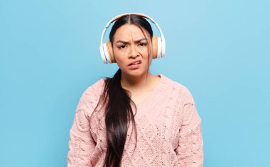 hispanic woman feeling puzzled and confused, with a dumb, stunned expression looking at something unexpected