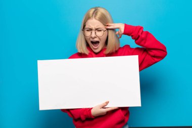 Sarışın kadın mutsuz ve stresli görünüyor, intihar jesti elle silah işareti yapıyor, kafasını işaret ediyor.