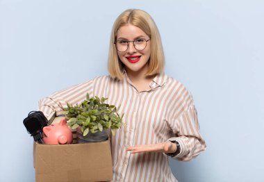Sarışın kadın mutlu bir şekilde gülümsüyor, mutlu hissediyor ve fotokopi alanında avucunun içinde bir konsept gösteriyor.