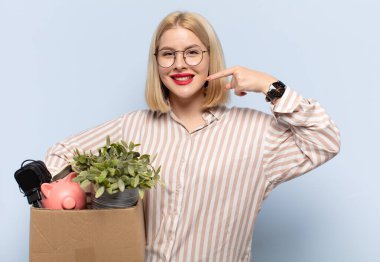 Sarışın kadın kendine güvenerek gülümsüyor. Geniş gülüşünü gösteriyor. Olumlu, rahat, tatmin olmuş bir tavır.
