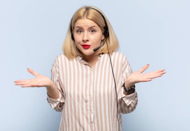 Sarışın kadın şaşkın ve şaşkın hissediyor, şüpheci, farklı seçenekleri tartıyor veya komik bir ifadeyle seçiyor.