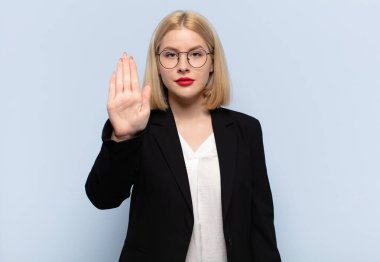 Sarışın kadın ciddi, sert, hoşnutsuz ve kızgın görünüyor.