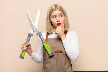 Sarışın kadın düşünüyor, kuşkulu ve şaşkın hissediyor, farklı seçenekleri var, hangi kararı vereceğini merak ediyor.