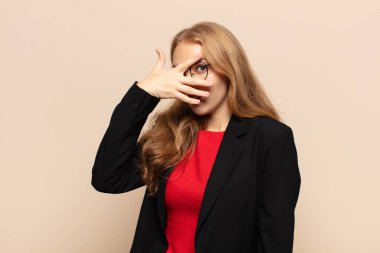 Sarışın kadın şok olmuş, korkmuş ya da korkmuş görünüyordu. Yüzü elle kaplıydı ve parmaklarının arasından bakıyordu.