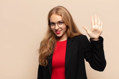 Sarışın kadın gülümsüyor ve arkadaş canlısı görünüyor, 5 ya da 5 numarayı gösteriyor, eli önde, geriye doğru sayıyor.