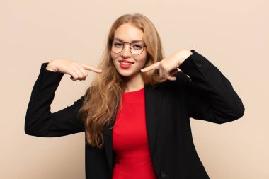 Sarışın kadın kendine güvenerek gülümsüyor. Geniş gülüşünü gösteriyor. Olumlu, rahat, tatmin olmuş bir tavır.