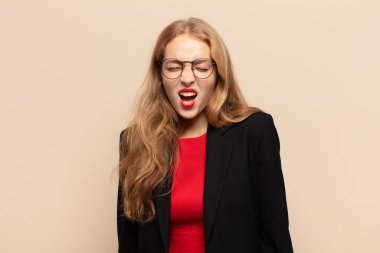 Sarışın kadın agresif bir şekilde bağırıyor, çok kızgın, sinirli, öfkeli ya da sinirli görünüyor.