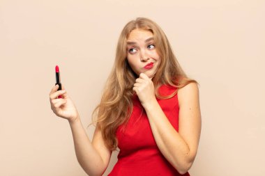 Sarışın kadın düşünüyor, kuşkulu ve şaşkın hissediyor, farklı seçenekleri var, hangi kararı vereceğini merak ediyor.