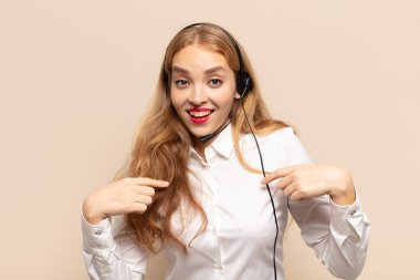 Sarışın kadın mutlu, şaşkın ve gururlu, heyecanlı, şaşkın bakışlarla kendini işaret ediyor.