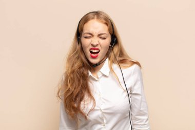 Sarışın kadın agresif bir şekilde bağırıyor, çok kızgın, sinirli, öfkeli ya da sinirli görünüyor.