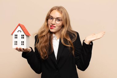 Sarışın kadın şaşkın ve şaşkın hissediyor, şüpheci, farklı seçenekleri tartıyor veya komik bir ifadeyle seçiyor.