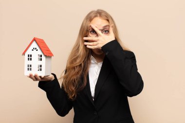 Sarışın kadın şok olmuş, korkmuş ya da korkmuş görünüyordu. Yüzü elle kaplıydı ve parmaklarının arasından bakıyordu.