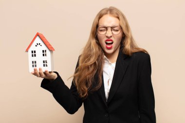 Sarışın kadın agresif bir şekilde bağırıyor, çok kızgın, sinirli, öfkeli ya da sinirli görünüyor.