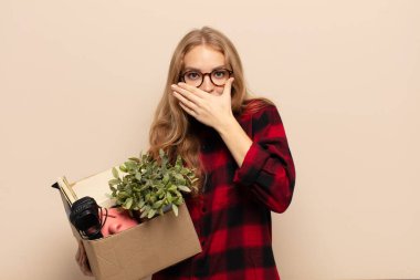 Sarışın kadın elleri ile ağzını kapatıyor, şok olmuş, şaşırmış bir ifadeyle, sır saklıyor ya da 