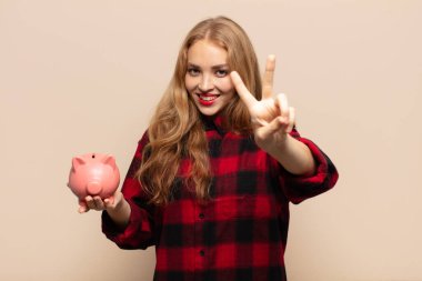 Sarışın kadın gülümsüyor ve mutlu görünüyor, kaygısız ve olumlu, zafer ya da huzur simgesi.