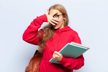 Sarışın kadın şok olmuş, korkmuş ya da korkmuş görünüyordu. Yüzü elle kaplıydı ve parmaklarının arasından bakıyordu.