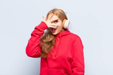 Sarışın kadın şok olmuş, korkmuş ya da korkmuş görünüyordu. Yüzü elle kaplıydı ve parmaklarının arasından bakıyordu.