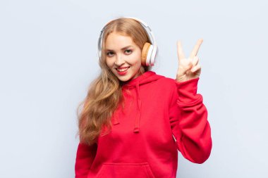 Sarışın kadın gülümsüyor ve arkadaş canlısı görünüyor. İki ya da iki numarayı gösteriyor. Elleri önde, geriye doğru sayıyor.